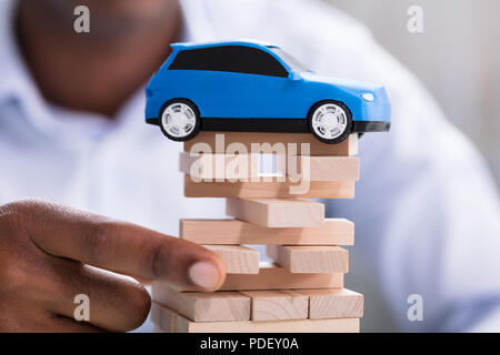 Close-up di mano di una persona blocchi di trattenimento con il giocattolo auto blu Foto Stock
