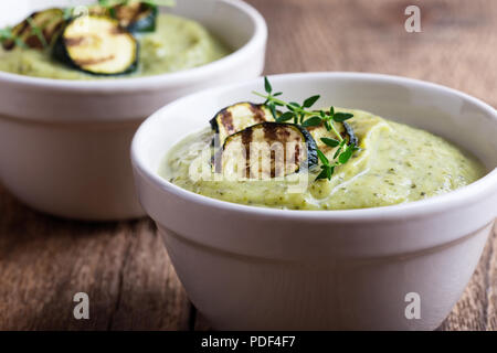Sana crema di zucchine la zuppa in ciotole di ceramica sul tavolo di legno Foto Stock