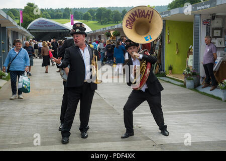 Maschio trio di musicisti vivace divertente persone, giocando & passeggiate sul viale degli stand commerciali - RHS Chatsworth Flower Show, Derbyshire, England, Regno Unito Foto Stock