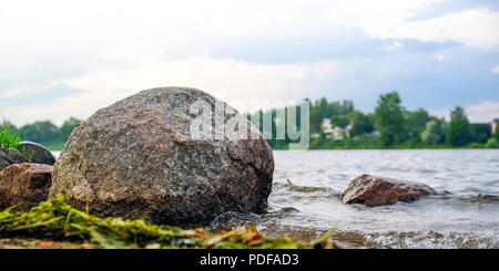 Limpido fiume con rocce porta verso le montagne illuminate dal tramonto. Contro il cielo blu. Foto Stock