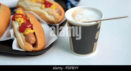 Il DOG, Salsa ketchup, il caffè con il latte in una tazza. Latte isolate su sfondo bianco. Foto Stock