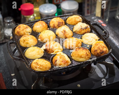 Takoyaki (polpo palle), un snack giapponese da alimentare l'area di Osaka, una cottura in ghisa takoyaki pan. Octopus Garden Restaurant, Osaka, Giappone. Foto Stock