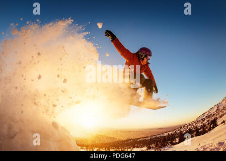 Snowboarder salta al tramonto con polvere di neve Foto Stock