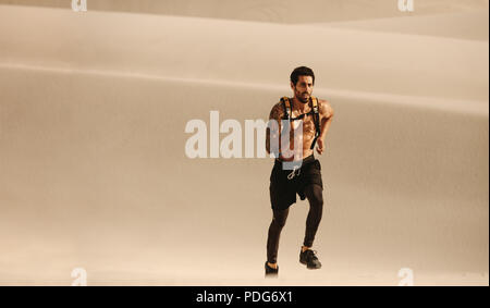 Giovane uomo sano che corre sulla sabbia del deserto. fitness man che corre su dune di sabbia. Foto Stock