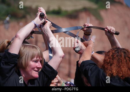 Frusta il gatto Rapper e ostruire, donna inglese del Team di danza, eseguendo un rapper ballo di spada a Sidmouth Folk Festival, East Devon, Regno Unito. Agosto, 2018. Foto Stock