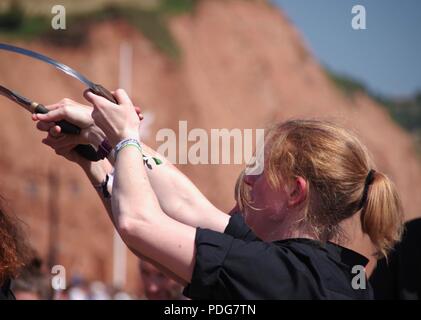 Frusta il gatto Rapper e ostruire, donna inglese del Team di danza, eseguendo un rapper ballo di spada a Sidmouth Folk Festival, East Devon, Regno Unito. Agosto, 2018. Foto Stock