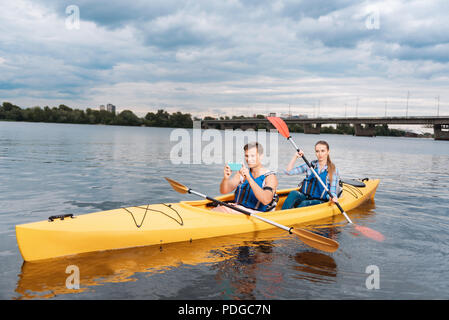 Uomo seduto in kayak con la sua moglie di scattare una foto di un bel paesaggio Foto Stock