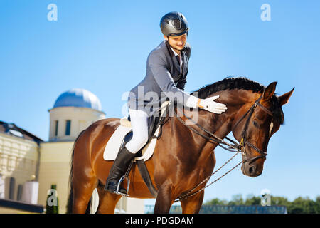 Bel uomo sorridente indossando il casco petting cavallo Foto Stock