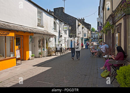 Persone turisti visitatori e negozi negozi negozi ristoranti nel centro della città in estate Ash Street Bowness su Windermere Cumbria Inghilterra Regno Unito Foto Stock