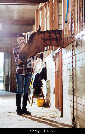 Caring horsewoman proveniente da stabile per cavallo di pulizia Foto Stock