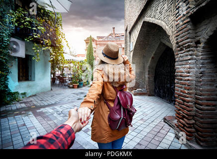 La donna nel cappello e giacca marrone che conduce l uomo della strada stretta nella vecchia, Georgia Foto Stock