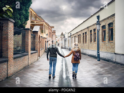 Donna turistiche in marrone cappello e Uomo in camicia rossa percorrendo a piedi il vecchio le antiche strade del centro di Tbilisi, Georgia Foto Stock