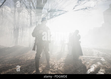 Rogachev, Bielorussia - Febbraio 25, 2017: Re-enactors vestito come il tedesco della Wehrmacht Soldato di fanteria nella guerra mondiale II In piedi In drammatico attraverso la retroilluminazione Foto Stock