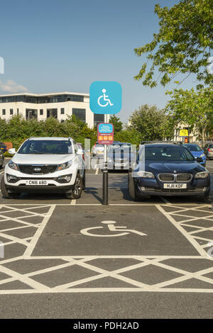 Segnaletica e marcature sulla terra per denotare una baia di parcheggio riservato per persone disabili Foto Stock