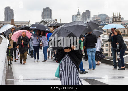 Bankside, Londra, Regno Unito. Il 9 agosto, 2018. I londinesi di ottenere i loro ombrelli e impermeabili come pioggia e temperature più basse sostituire la recente ondata di caldo. Michael Heath/Alamy Live News Foto Stock