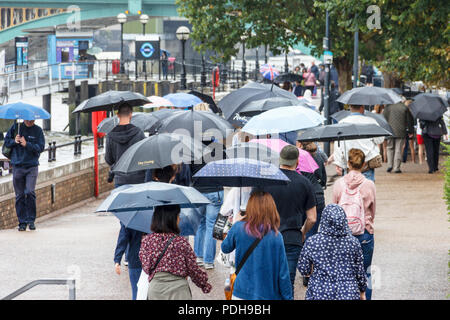 Bankside, Londra, Regno Unito. Il 9 agosto, 2018. I londinesi di ottenere i loro ombrelli e impermeabili come pioggia e temperature più basse sostituire la recente ondata di caldo. Michael Heath/Alamy Live News Foto Stock