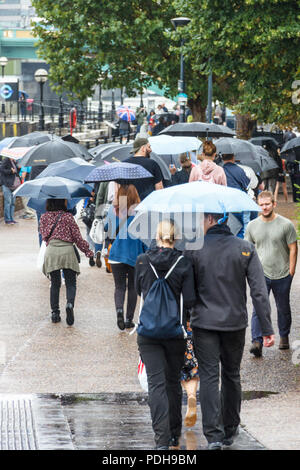 Bankside, Londra, Regno Unito. Il 9 agosto, 2018. I londinesi di ottenere i loro ombrelli e impermeabili come pioggia e temperature più basse sostituire la recente ondata di caldo. Michael Heath/Alamy Live News Foto Stock