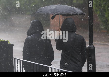 Londra. Regno Unito 10 ago 2018 - Due donne ripari sotto un ombrello durante pioggia pesante tra le magie di sole a Londra. Secondo il Met Office le perturbazioni atmosferiche è probabilmente destinata a continuare nei prossimi giorni. Credito: Dinendra Haria/Alamy Live News Foto Stock