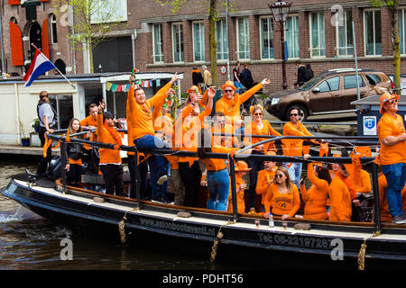 Amsterdam, Paesi Bassi - Aprile 2018: Barche sui canali di Amsterdam con la gente celebra il re del giorno in Paesi Bassi Foto Stock