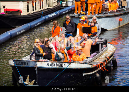 Amsterdam, Paesi Bassi - Aprile 2018: Barche sui canali di Amsterdam con la gente celebra il re del giorno in Paesi Bassi Foto Stock