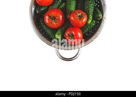 Crudo Intero Lavate i pomodori e cetrioli in uno scolapasta isolati su sfondo bianco. Vista da sopra. Lay piatto. Foto Stock