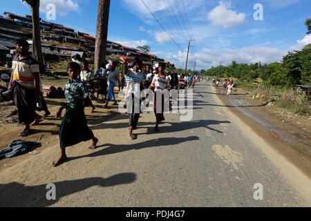 I rifugiati Rohingya a piedi attraverso la strada di fronte al Balukhali Refugee Camp. Cox's Bazar, Bangladesh Foto Stock