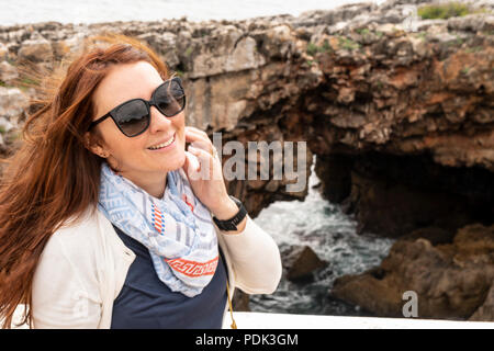 Donna in posa di fronte della Gola del Diavolo, La Garganta do diabo, formazione di roccia a Cascais, Portogallo Foto Stock