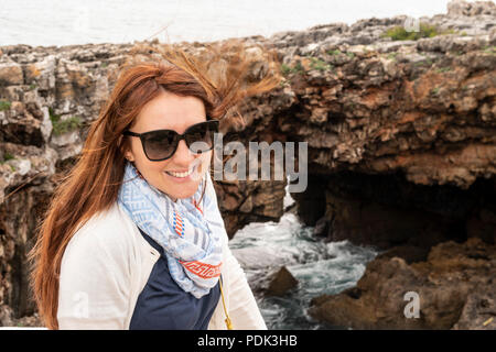 Donna in posa di fronte della Gola del Diavolo, La Garganta do diabo, formazione di roccia a Cascais, Portogallo Foto Stock