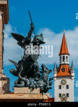 Monaco di Baviera, Germania - 29 Luglio 2018: Statua di putto che uccide il drago sulla colonna mariana il piedistallo, Marienplatz con Spielzeugmuseum in background Foto Stock