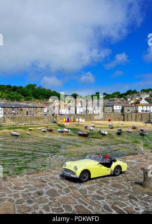 Trionfo giallo TR3 lasciando porto parcheggio auto in,Mousehole,Cornwall,l'Inghilterra,UK Foto Stock