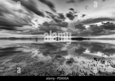 Perfetta e simmetrica nuvole e isole riflessioni su un lago, rendendo le forme astratte Foto Stock