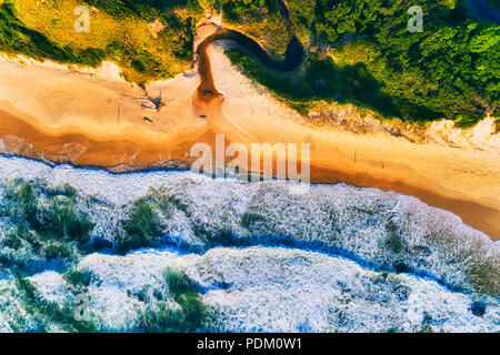 Le onde di laminazione colpendo appartata Shelly sabbiosa spiaggia di Nambucca capi città in Australia NSW Costa Nord durante il bel tempo in morbida luce mattutina. Foto Stock