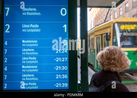 Orario elettronico display che mostra stimato tempi di arrivo del tram con il tram arriva alla fermata del tram su Aleksanterinkatu Street in Helsinki Finlandia Foto Stock