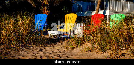 Sedie da spiaggia incastonata nella sabbia con rosso, blu, verde, giallo sedie. (4) Foto Stock