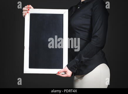 Cameriera azienda lavagna vuota. Giovani professionisti donna in maglia nera con lavagna vuota. Foto Stock