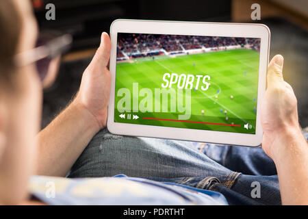 L'uomo guardare sport su tablet. Il calcio e la partita di calcio in diretta streaming e lettore video sullo schermo. Pay per view (PPV) servizio. Foto Stock