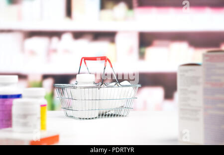 Farmacia con farmaci e ripiani. Carrello della spesa pieno di medicina e flaconi portapillole sul contatore in farmacia. Foto Stock