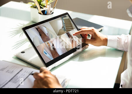 Close-up di un imprenditore il canto controllo telecamera TVCC filmati sul computer portatile Foto Stock