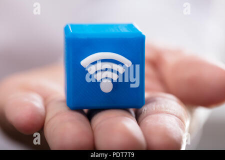 Close-up di mano di una persona azienda blu blocco cubico con icona wireless Foto Stock