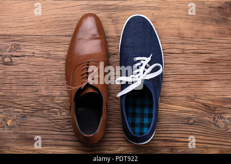 Vista in elevazione di due diverse scarpa su sfondo di legno Foto Stock