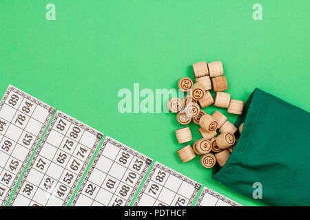 Lotto in legno Barili con panno verde sacco e carte da gioco su sfondo verde. Gioco di bordo del lotto. Vista da sopra con copia spazio sulla sinistra Foto Stock