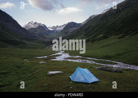 Camping con una piccola tenda blu in Piazza Tian Sham montagne, Kirghizistan. Tian Shan montagne sono alcuni dei luoghi più belli per fare trekking. Foto Stock