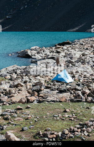 Camping con una piccola tenda blu in Piazza Tian Sham montagne, Kirghizistan. Tian Shan montagne sono alcuni dei luoghi più belli per fare trekking. Foto Stock