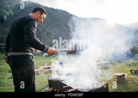 Famiglia in Kirghizistan cucinare la cena fuori sul fuoco Foto Stock