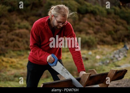 Un uomo taglio del legno in una posizione reale Foto Stock