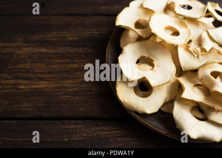 Apple chip di frutta sul legno scuro, sfondo spazio copia, vegana sani snack. Foto Stock