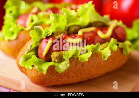 Hot Dog con lattuga, senape e ketchup su sfondo di legno Foto Stock