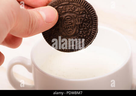 KRASNODAR, Russia - 17 Giugno 2018: Oreo cookie isolato in mano, dunk nel latte. Costituito da due wafer al cioccolato con un dolce ripieno di panna in betwe Foto Stock