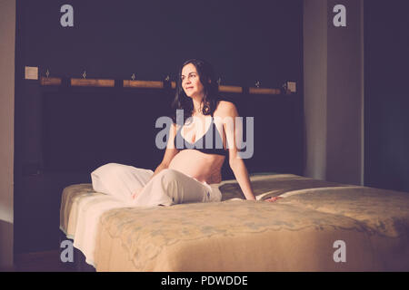 Gravidanza caucasico bella donna seduta sul pavimento e respirare per rilassarsi. Il nuovo concetto di vita a casa. Da soli in camera da letto il sorriso e la felicità per n Foto Stock