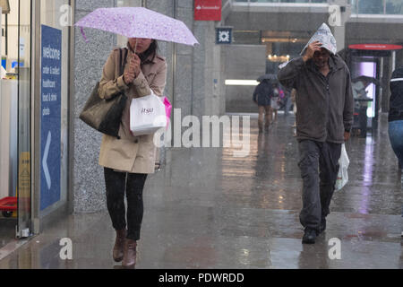 Gli acquirenti ottenere catturati in una pesante pioggia su London Victoria Street. Foto Stock